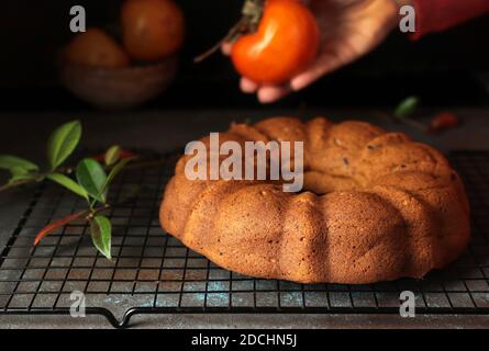 Bundt cake with persimmon, served on table. Selective focus. Stock Photo