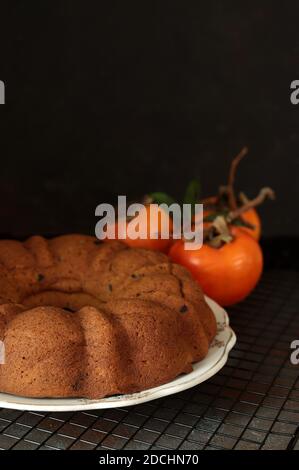 Bundt cake with persimmon, served on table. Selective focus. Stock Photo