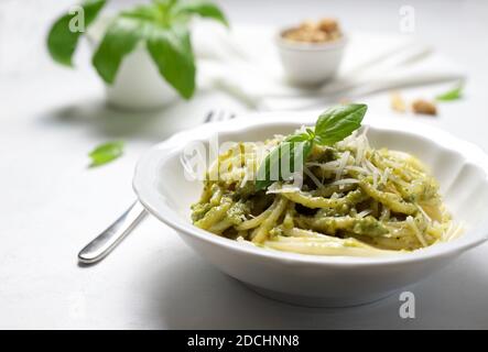 Spaghetti pasta with fresh basil pesto sauce and parmesan cheese on white bowl. Closeup Stock Photo