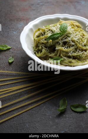 Pasta spaghetti with pesto sauce and fresh basil leaves. Dark background. Selective focus Stock Photo