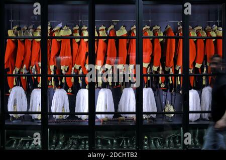 Gives & Hawkes cabinet containing a row of scarlet uniforms, embellished with gold tassels and braided cord aiguillettes. Stock Photo
