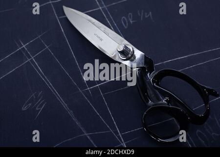 United Kingdom /London /Savile Row/ Tailors scissors lying on fabric marked in chalk with the pattern of the garment in a close up at Norton & Son’s. Stock Photo