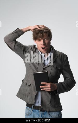 Young brown haired surprised man smiling touching head gesture on camera isolated on white background. Wow expression Stock Photo