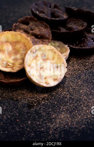 Chocolate coated hazelnut and rice florentines covered in cocoa powder.  White, milk and dark chocolate selection Stock Photo