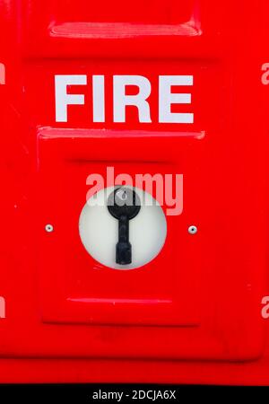 A vertical shot of a red fire alarm against a wall Stock Photo