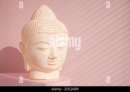 White Buddha bust on pastel pink background Stock Photo