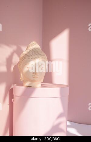 White Buddha bust on pastel pink background Stock Photo