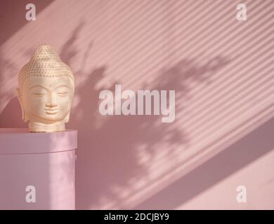 White Buddha bust on pastel pink background Stock Photo