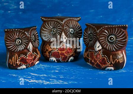 Cairo , November 16.2020 : Three intricately hand carved wood owls figurines on abstract watercolor background. family concept. Stock Photo