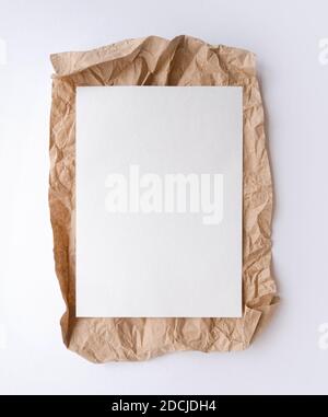 White sheet lying on craft crumpled paper. Flatlay Stock Photo