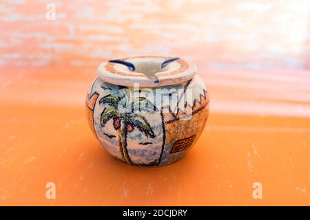 Beautiful palm painting in handmade pottery Ashtray on gradian yellow abstract background for house Decoration. Stock Photo