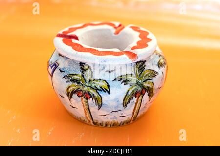 Beautiful palm painting in handmade pottery Ashtray on gradian yellow abstract background for house Decoration. Stock Photo