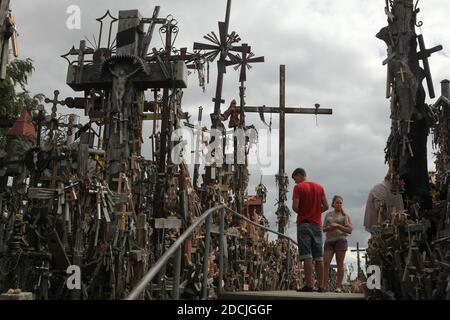 Two young pilgrims visit the Hill of Crosses near Šiauliai in Lithuania. The most important Lithuanian pilgrimage site is located some 12 km from the town of Šiauliai. Nobody has ever tried to count how many large and small crosses are actually installed on the hill, but it is believed there are at least two hundred thousand crosses here. And every day dozens or even hundreds of new crosses are added by pilgrims from all over the world. Stock Photo