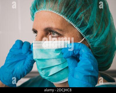 Portrait healthcare professional woman with protection against covid 19 putting her mask Stock Photo