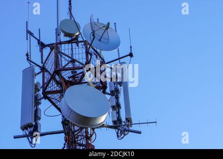 Telecommunications tower with 4G, 5G transmitters. cellular base station with transmitting antennas on a telecommunications tower against the blue sky Stock Photo