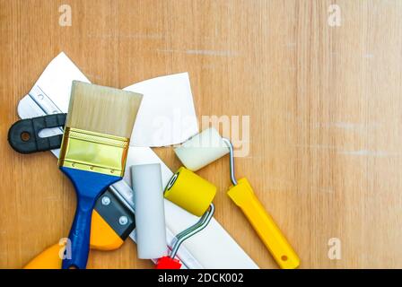 Home repair tools on wooden background. Foam and rubber rollers for wall coloring and a spatula close up. Stock Photo