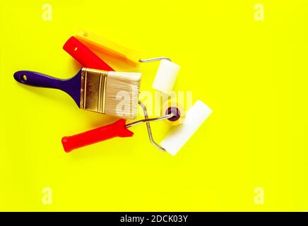 Home repair tools on bright yellow background. Foam rollers and synthetic brushes for wall coloring. Stock Photo