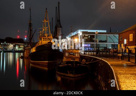 Boats are moored on the quayside of Prince's Wharf beside the M Shed museum at night on Bristol's Floating Harbour. Stock Photo