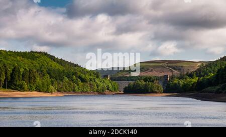 Low water reveals the shores of Derwent Reservoir, under Howden Dam and the wooded hills of the Derbyshire Peak District. Stock Photo