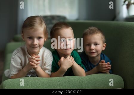 Beautiful children lie on the couch at home, looking at the camera. Stock Photo