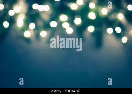 dark blue green blurry christmas background with bokeh garland lights and blurred spruce twigs border Stock Photo