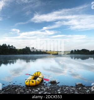 Yellow packraft rubber boat with red padle on a sunrise river. Packrafting. Active lifestile concept Stock Photo