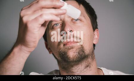 Young Caucasian man holds nasal spray for rhinitis and allergies in his hands and studies composition and instructions for use. Medication or drugs Stock Photo