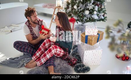 A young couple having fun with Xmas presents on a beautiful holiday morning at home. Christmas, relationship, love, together Stock Photo