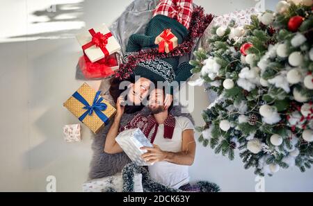 A lovely couple has wonderful time on Christmas at home together on a beautiful holiday morning. Christmas, relationship, love Stock Photo