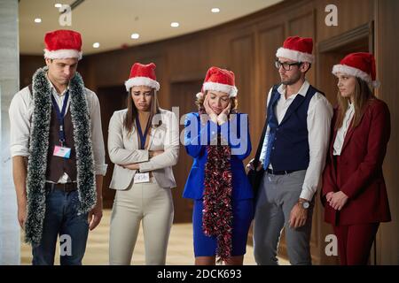 Group of unsatisfied colleagues at workplace sad because they have to work on New Year's eve. Together, New Year, celebration Stock Photo