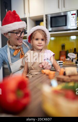 Grandma likes to be with granddaughter in the kitchen for a Xmas in a festive atmosphere. Christmas, family, together Stock Photo
