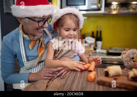 Grandma and granddaughter preparing Xmas meal in the kitchen in cheerful atmosphere together. Christmas, family, together Stock Photo