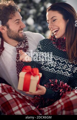 A young couple in love spending wonderful time together giving Xmas presents at home on a beautiful holiday morning. Christmas, relationship, love, to Stock Photo