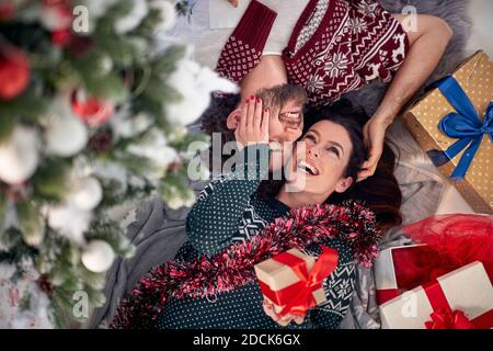 A young couple in love lying on the floor at home surrounded by Xmas presents on a beautiful holiday morning. Christmas, relationship, love, together Stock Photo