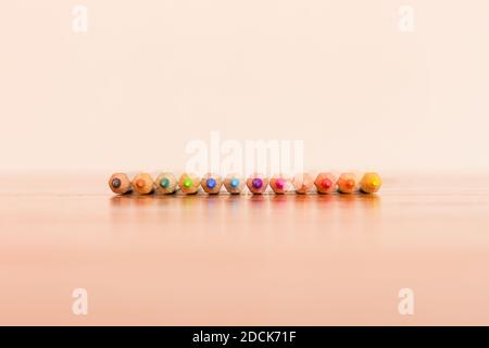 Front perspective of a row of twelve color pencils aligned on brown and white background Stock Photo