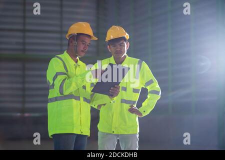 Asian industrial engineers in warehouse new project while. They Make Showing Gestures. They Work in construction site Stock Photo