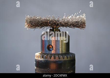 Metal nozzle brush for electric drill for brushing wood on gray background Stock Photo