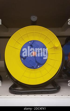 Yellow electrical extension cord on a take-up reel with four pins Stock Photo