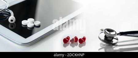 stethoscope and drug pill and pink red heart and tablet computer for tele medicine health concept on white background Stock Photo