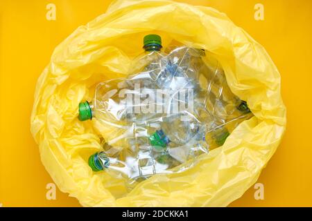 Plastic package with plastic bottles on yellow background. Recycling concept Stock Photo
