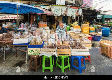 Bangkok, Thailand - December 7, 2019: Vendor at a market selling sun dried fish salted for preservation (Thai traditional food) in Bangkok, Thailand. Stock Photo