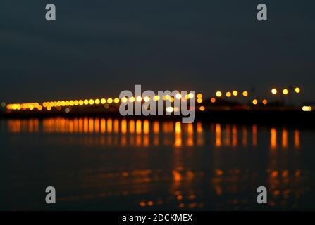 Abstract Blurred Sea Bridge at Night with the Reflections of Lighting on the Sea Stock Photo