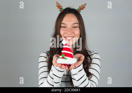 A happy woman holds a Christmas decoration. Grey background. High quality photo Stock Photo