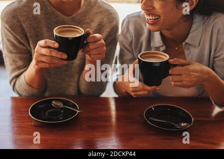 Cropped shot of two friends having coffee together in a coffee shop. Woman friends in a cafe having coffee. Stock Photo