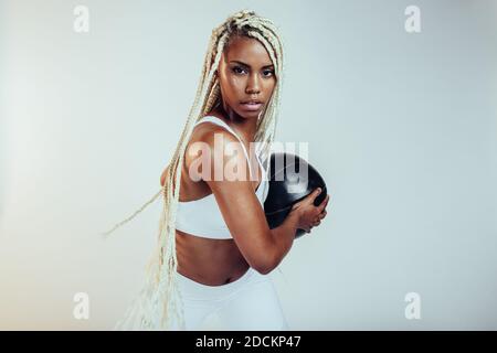 fitness woman exercising with medicine ball on white background. African american with long braided hair doing fitness workout. Stock Photo