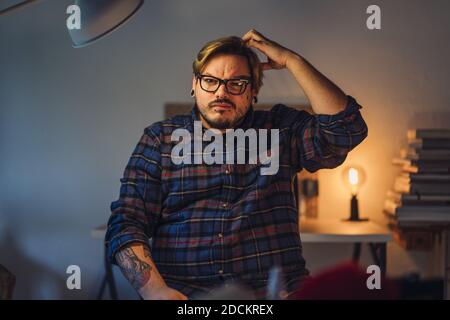 A closeup portrait of a casual cute hipster man in glasses scratching his head, thinking Stock Photo