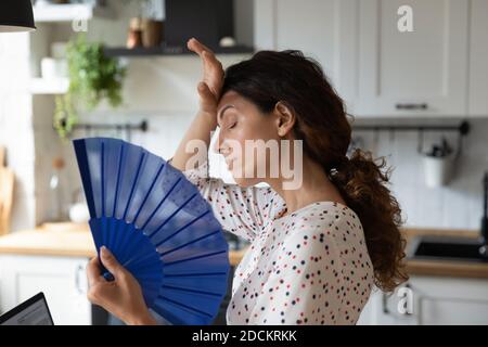 Unwell young woman feel overheated using hand fan Stock Photo