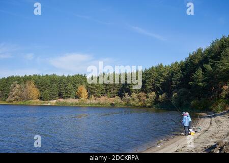 Elderly people man and woman are fishing on the river bank. Active lifestyle concept in old age Stock Photo