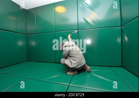 a man is kneeling alone in a green padded cell Stock Photo