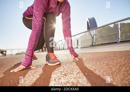 Ready to go. Cropped shot of active mature woman wearing sportswear standing in start position, ready for running outdoors on a sunny day Stock Photo